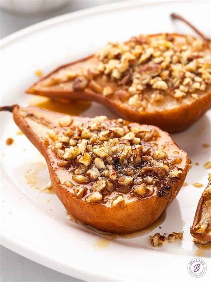 Baked pears on a plate with yogurt and granola.