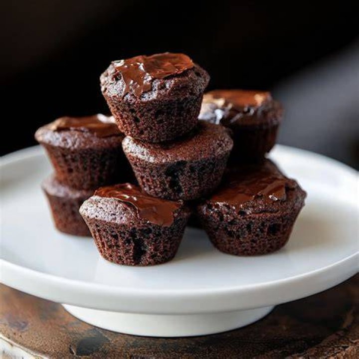 Half of a brownie bite topped with chocolate frosting and a raspberry.