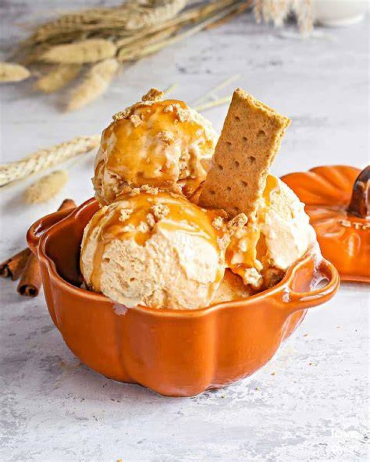 Pumpkin ice cream in a metal pan topped with crushed cookies.