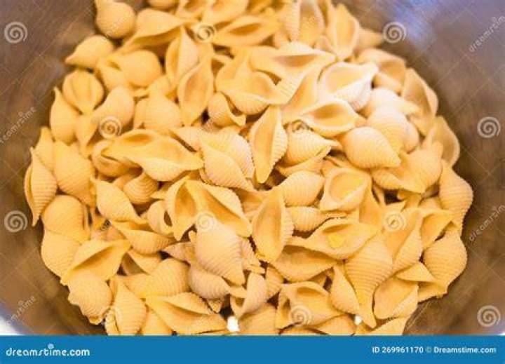 Saucepan of pasta shells with pesto and peas.