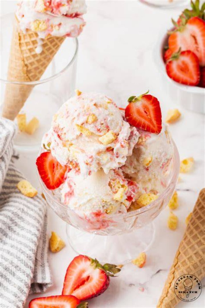 Scoops of strawberry shortcake ice cream in a white bowl.