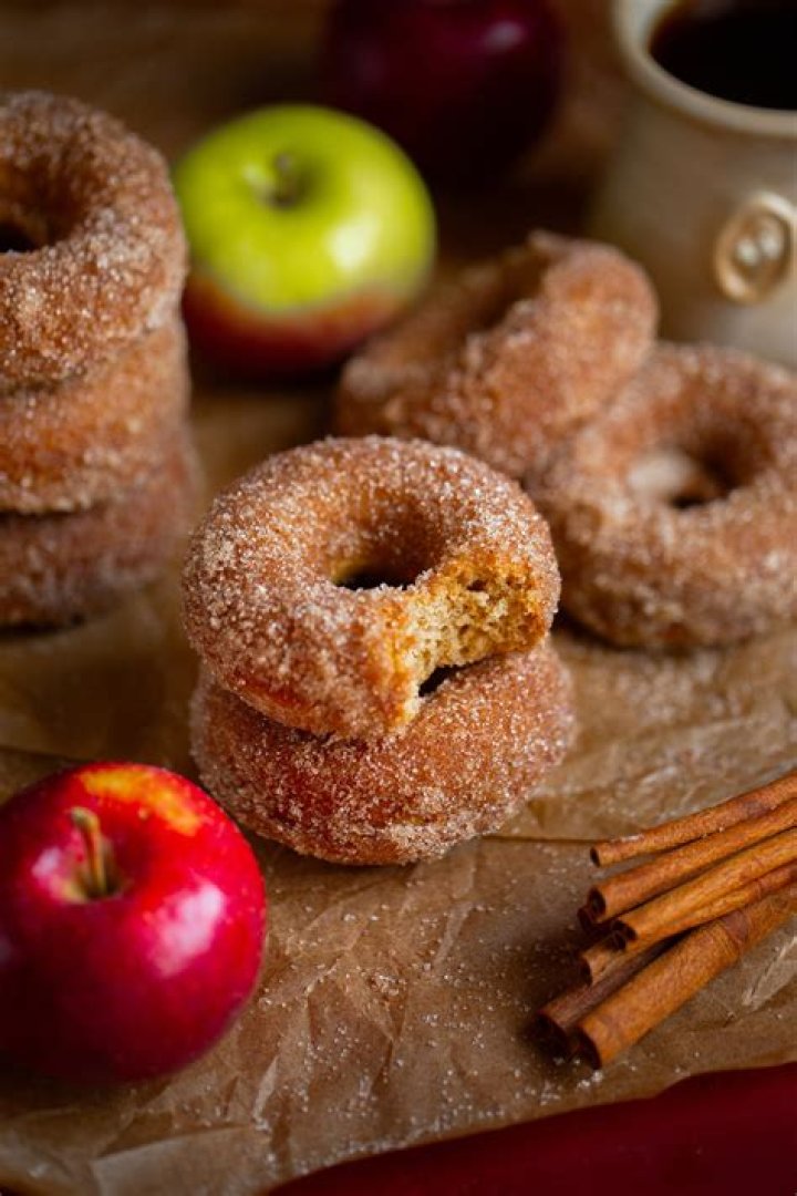 Slices of apple cider donut cake on a white platter next to a red and white striped towel.